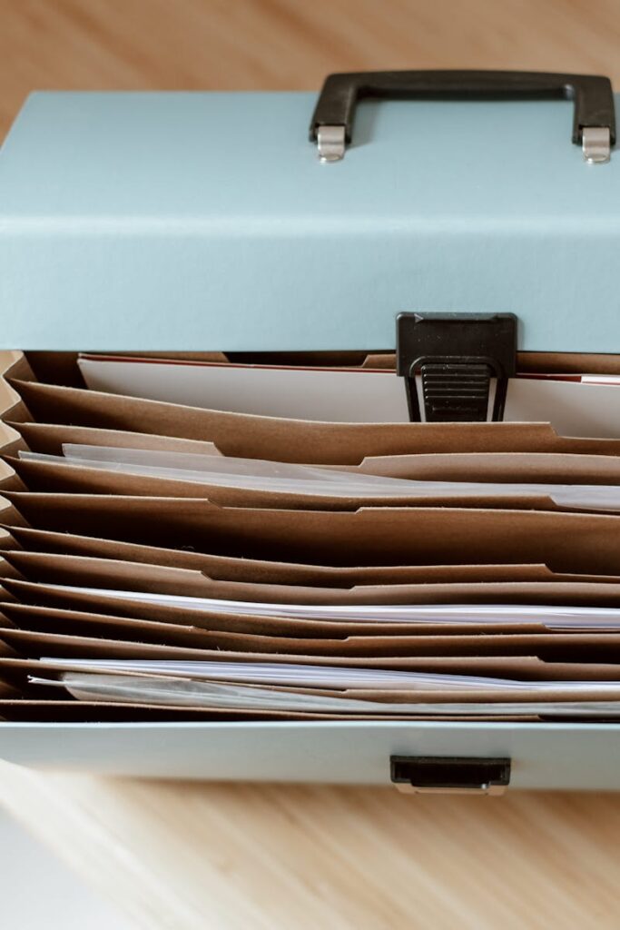 From above of briefcase for documents with papers placed on wooden table in daytime